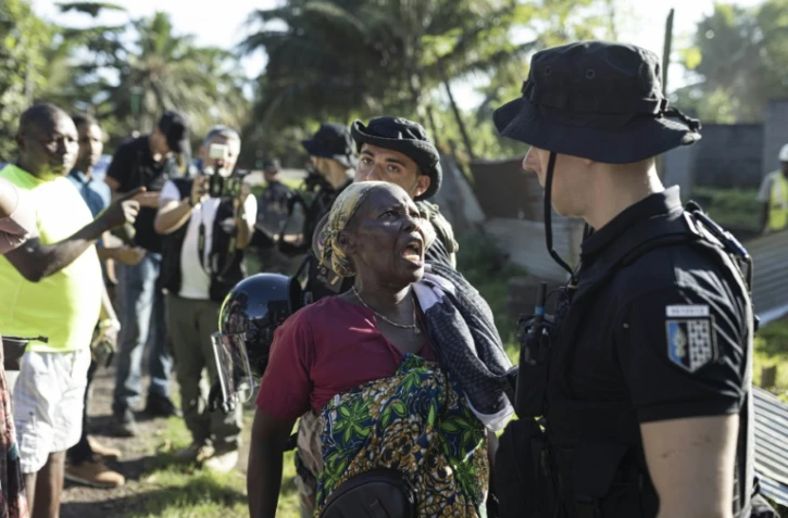 Une femme interppelle un gendarme français lors de la démolition d'un campement informel à Longoni, sur la commune de Koungou, le 27 avril 2023 à Mayotte