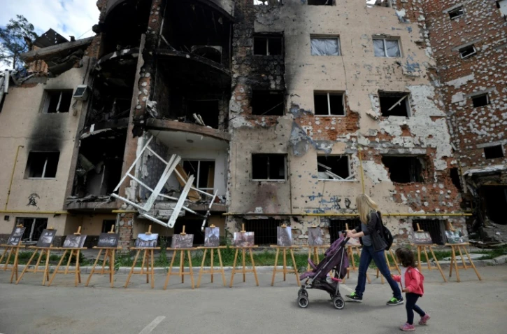 Une femme et sa fille passent devant un immeuble détruit à Irpin, près de Kiev, le 16 juin 2022