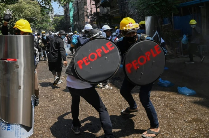 Des manifestants pro-démocratie se défendent face aux forces de l'ordre birmanes, à Rangoun, le 7 mars 2021
