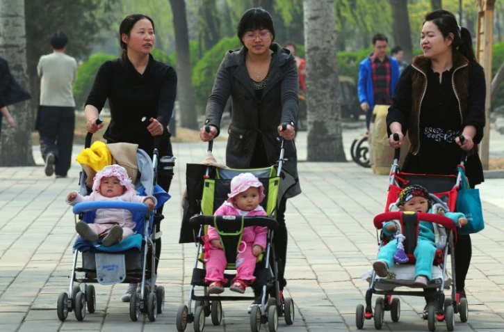 Des femmes avec des enfants en poussette à travers un parc de Pékin, le 5 avril 2011