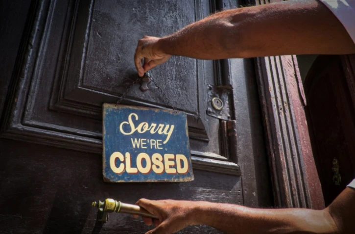 Un employé accroche un panneau "Désolé, on est fermé" à la porte de la cafétéria El Café, le 16 avril 2020 à La Havane
