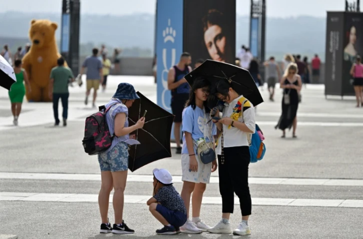 Des touristes se protègent du soleil avec des ombrelles, le 18 juillet 2023 à Madrid, pendant une vague de chaleur en Espagne