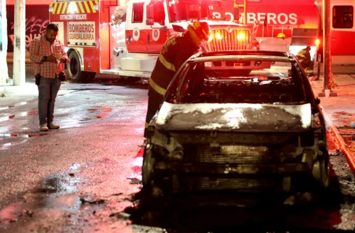 Un journaliste mexicain prend des photos d'un véhicule incendié, à Guadalajara, dans l'État de Jalisco, au Mexique, le 28 février 2022