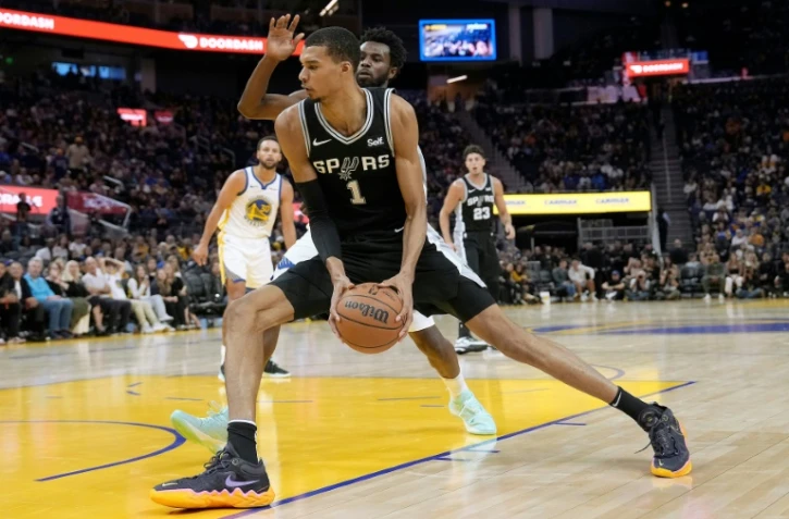 Le Français Victor Wembanyama, des San Antonio Spurs, passe Andrew Wiggins, des Golden State Warriors, lors d'un match d'avant-saison entre les deux franchises NBA, à San Francisco, le 20 octobre 2023