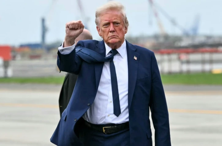 Le président américain Donald Trump lève le poing alors qu'il descend de l'Air Force One à son arrivée à l'aéroport international de Newark Liberty à Newark, New Jersey, le 26 avril 2025