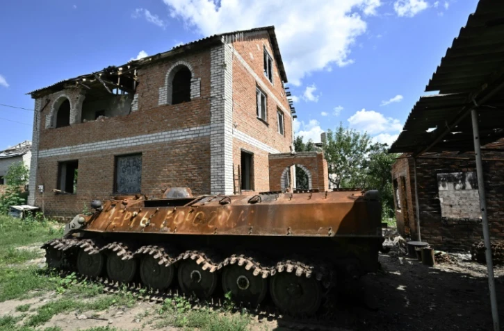 Un blindé russe détruit devant une maison endommagée, le 28 juillet 2022 à Mala Rogan, dans la région de Kharkiv, en Ukraine
