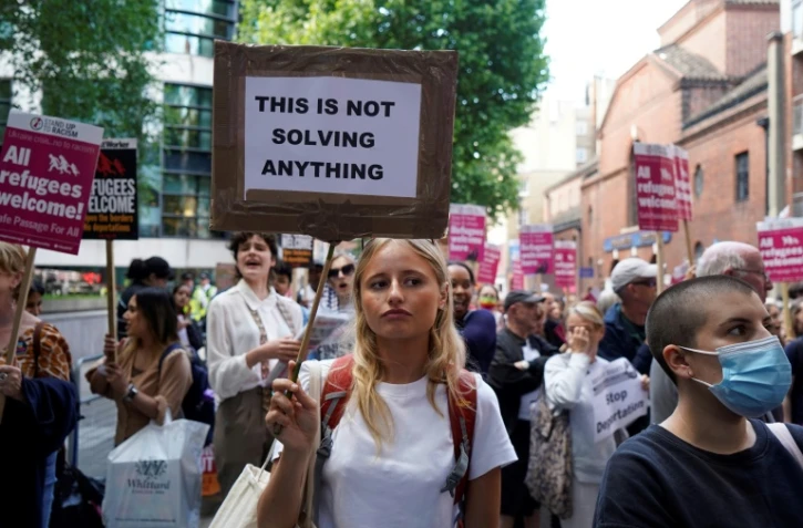 Une manifestante contre les expulsions de migrants du Royaume-Uni vers le Rwanda brandit une pancarte où il est écrit "Cela ne résoudra rien", devant le ministère britannique de l'Intérieur à Londres, le 13 juin 2022 
