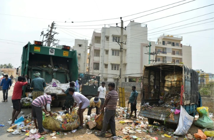 Des employés municipaux ramassent des ordures dans une zone résidentielle de Bangalore, le 11 janvier 2017 en Inde