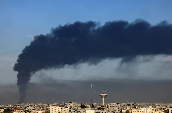 Une photo prise de Rafah montre un nuage de fumée au dessus de Khan Younès dans le sud de Gaza après des bombardements israéliens le 21 janvier 2024
