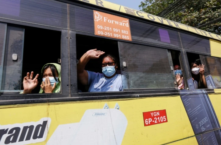 A bord d'un bus, des personnes libérées de la prison d'Insein à Rangoun (Birmanie) font le salut à trois doigts symbole de résistance, le 24 mars 2021