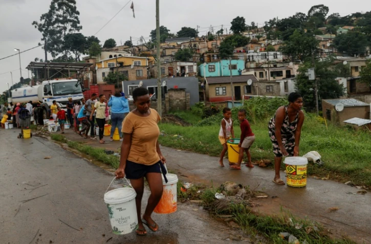 Des résidents du quartier de Bhambayi viennent s'approvisionner en eau potable après la rupture des canalisations ravagées par les inondations, à Durban le 15 avril