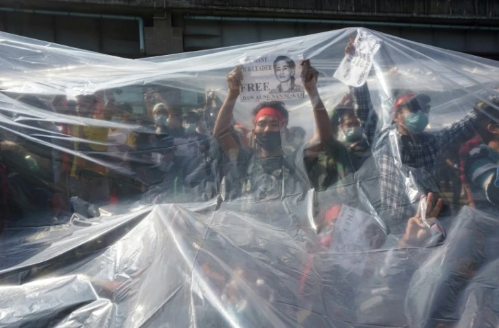 photo prise le 9 février 2021 montrant des manifestants en Birmanie sous un plastique les protégeant des canons à eau de la police à Rangoun