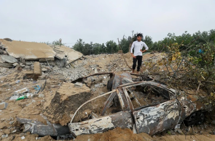 Un Palestinien se tient près d'une voiture et d'une habitation détruites par une frappe israélienne à Khan Younès, dans le sud de la bande de Gaza, le 11 mai 2023