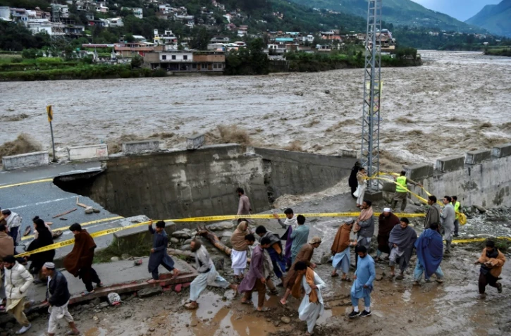Des personnes se rassemblent devant une route endommagée par inondations consécutives aux fortes pluies de mousson dans la vallée de Swat, dans le nord du Pakistan, le 27 août 2022