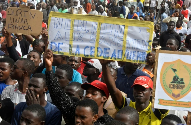 Des manifestants favorables aux militaires putschistes brandissent une banderole contre la Communauté économique des Etats d'Afrique de l'ouest (Cedeao), le 3 août 2023 à Niamey au Niger