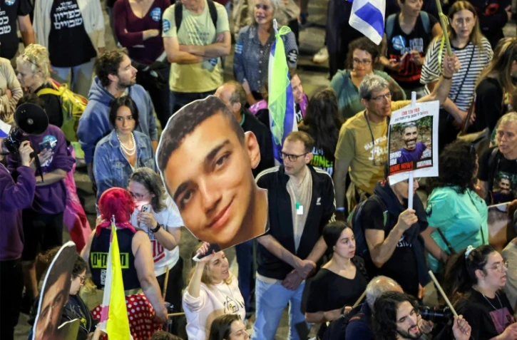 Une manifestante tient une photo géante de l'otage israélo-américain Edan Alexander, au centre, le 15 mars 2025, lors d'une manifestation à Tel Aviv, en Israël
