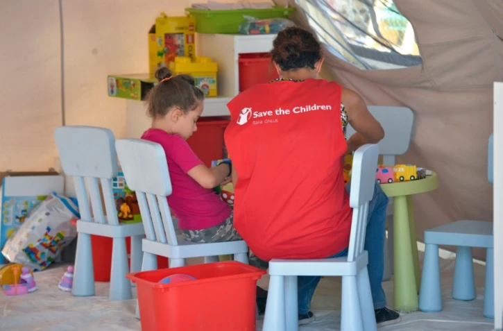 Un membre de l'ONG Save the Children près d'un enfant dans un campement à Amatrice le 27 août 2016