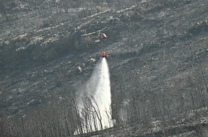 Un hélicoptère de la Sécurité civile déverse sa cargaison d'eau près du village de Coustouge, dans l'Aude touchée par des incendies, le 8 août 2025 