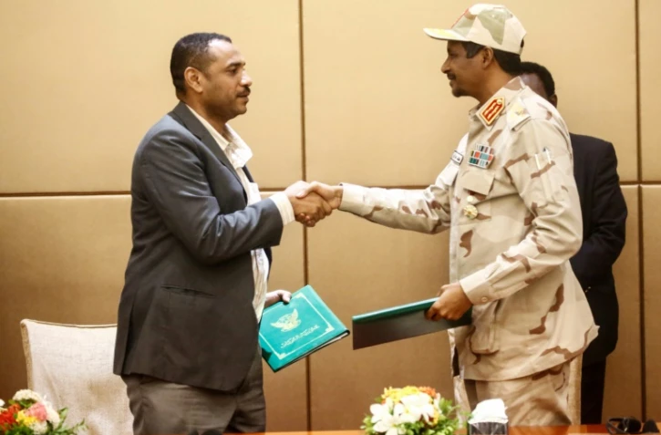 Le général Mohamed Hamdan Daglo (D), N°2 du Conseil militaire de transition, et le leader de la contestation Ahmed Rabie échangent une poignée de mains après avoir signé la déclaration constitutionnelle, le 4 août 2019 à Khartoum