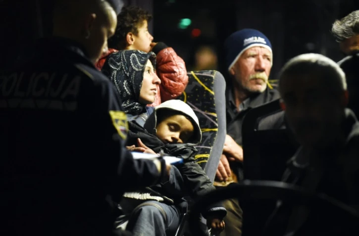 Des policiers solvènes enregistrent les migrants à  bord d'un bus le 21 octobre 2015 à Brezice en Solvénie