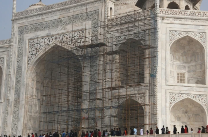Des touristes visitent le Taj Mahal et passent devant des échafaudages installés pour rénover le monument, à Agra en Inde, le 3 janvier 2018