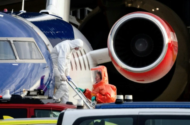 Une personne en combinaison blanche débarque le 6 mai 2026 d'un avion médicalisé Bombardier Challenger 605 censé transporter des passagers du bateau de croisière MV Hondius touché par une épidémie d'hantavirus