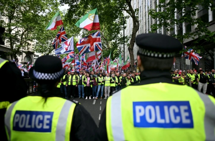 Des policiers face à des partisans de Tommy Robinson, militant d'extrême droite britannique, rassemblés pour une marche organisée par Unite The Kingdom, le 16 mai 2026 à Londres