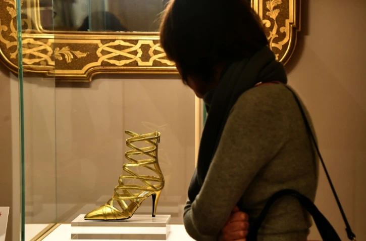 Une visiteuse de l'exposition "Aux pieds des dieux" admire une chaussure au Palais Pitti de Florence, le 30 janvier 2020 en Italie