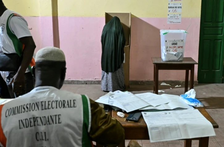 Une personne vote lors des élections législatives en Côte d'Ivoire, sous la surveillance d"un membre de la commission électorale indépendante, à  Abidjan le 27 décembre 2025