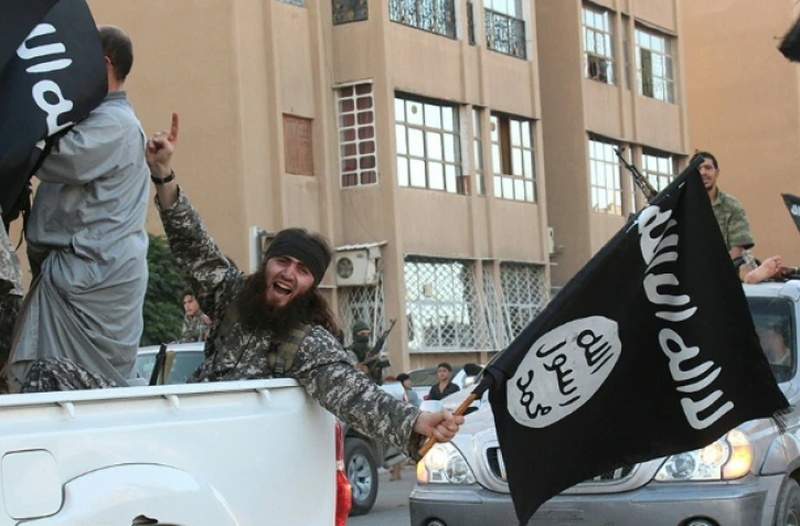 Une image diffusée par l'organe de presse jihadiste Welayat Raqa le 30 juin 2014 montre un membre du groupe État islamique (EI) défila un drapeau de l'EI à la main dans une rue de la ville syrienne de Raqa. 