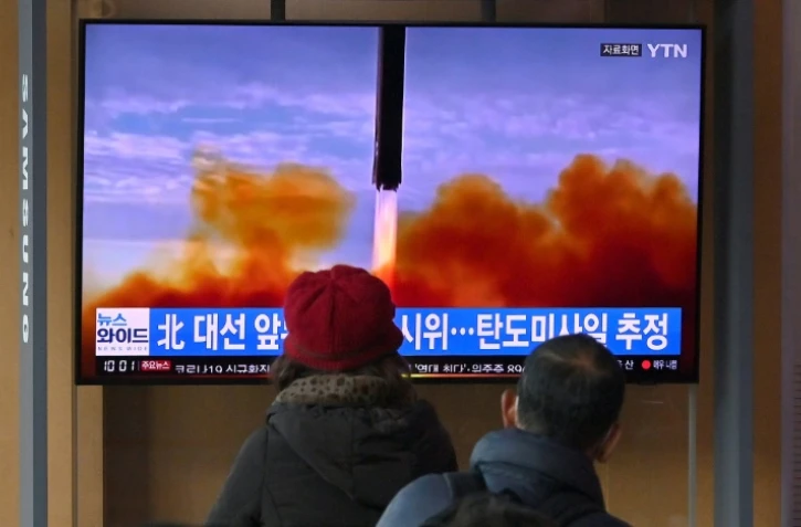 Des passants regardent un écran de télévision montrant un lancement de missile par la Corée du Nord, le 5 mars 2022 à Séoul