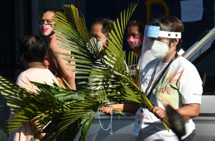 Des fidèles philippins se dirigent vers l'église pour le dimanche des Rameaux, le 5 avril 2020,à Manille