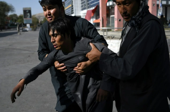 Des afghans aident un de leur ami blessé lors de l'attaque par des hommes armés d'une mosquée chiite de Kaboul, le 25 août 2017
