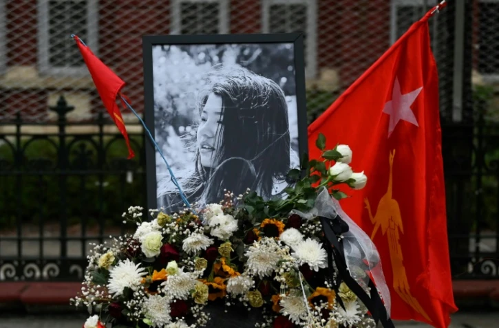 Des fleurs, un drapeau de la Ligue nationale pour la démocratie et un portrait, en hommage à Mya Thwate Thwate Khaing, première victime de la répression, à Rangoun le 19 février 2021