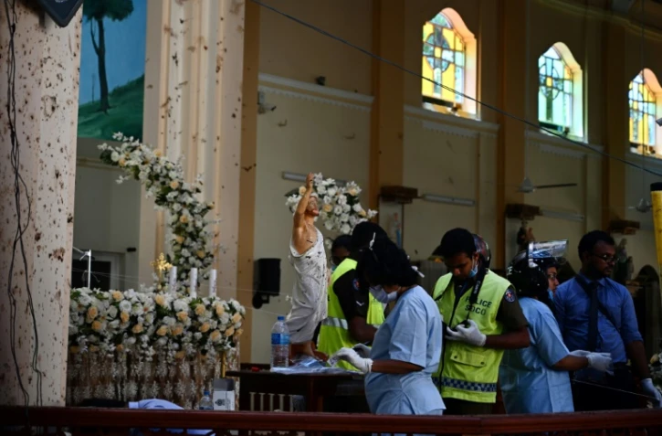 Du personnel de sécurité relèvent des traces dans l'église Saint-Sebastien de Negombo, le 22 avril 2019 au lendemain des explosions meurtrières