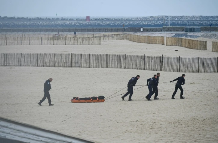 Des agents de police évacuent un corps découvert sur la plage de Calais, d'où de nombreux migrants tentent la périlleuse traversée de la Manche, le 6 novembre 2024