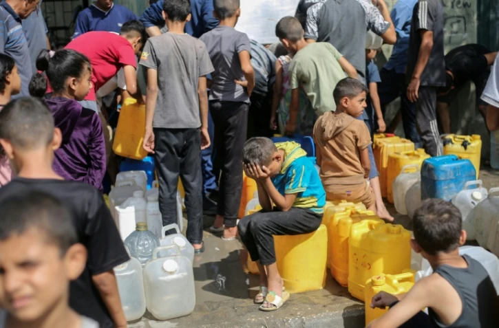 Des enfants palestiniens affluent à une distribution d'eau à Nousseirat,  dans le centre de la bande de Gaza, le 4 septembre 2025 