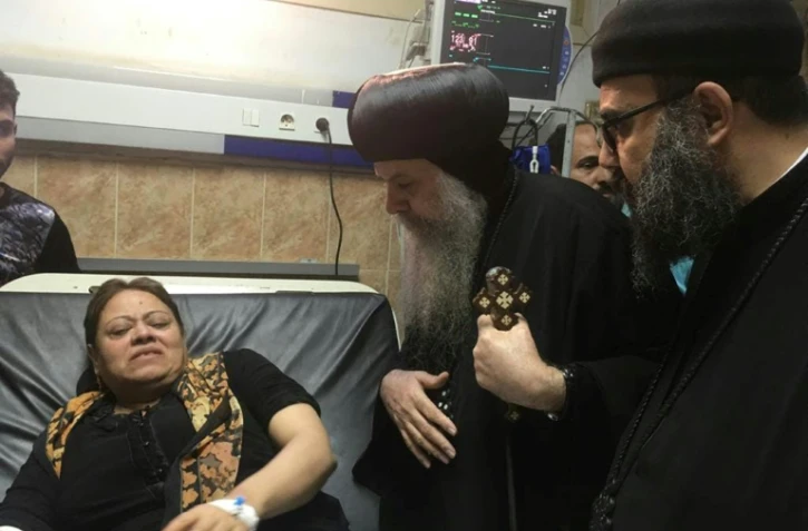 Un prêtre copte parle à une femme dans un hôpital de Beni Mazar, au sud du Caire, le 2 novembre 2018 après une fusillade sur un bus transportant des coptes dans la région de Minya