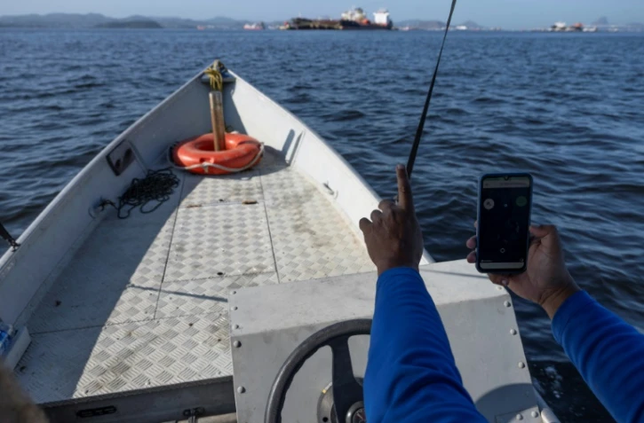 Alexandre Anderson de Souza, président de l'association de pêcheurs Ahomar, utilise une application pour dénoncer des délits environnementaux, le 1er août 2024, à Rio de Janeiro