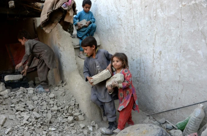 Des enfants aident leurs parents à la reconstruction de leur maison détruite par un tremblement de terre, le 29 octobre 2015 dans la province de Nangarhar, dans l'est de l'Afghanistan