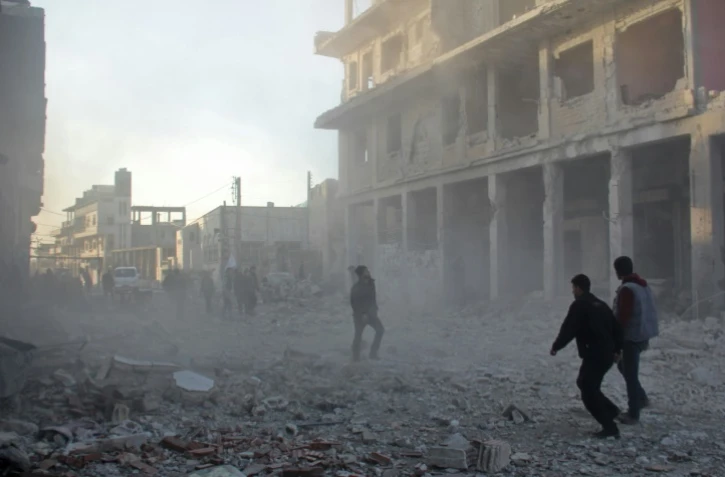 Des Syriens courent dans les débris de la ville de Binnish près d'Idleb après un raid aérien, le 12 janvier 2017