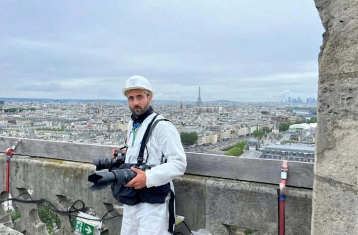 Le photographe de l'Agence France-Presse Julien De Rosa sur une tour de Notre-Dame avant la cérémonie d'ouverture des JO, le 26 juillet 2024 à Paris