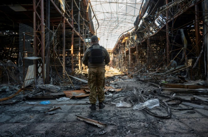 Un policier ukrainien recueille des éléments sur la destruction d'un des plus grands marchés européens de vêtements, "Barabashovo", à Kharkiv (est de l'Ukraine) le 16 mai 2022