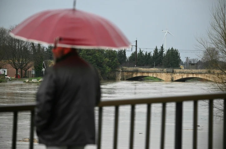 Un passant observe le débordement de l'Aude après des fortes pluies à Coursan, le 19 janvier 2026 dans l'Aude