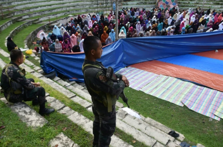 Des membres des forces spéciales de police montent la garde pendant que des musulmanes qui ont fui les combats à Marawi entre les forces armées philippines et les islamistes prient lors de l'Aïd el-Fitr à Iligan, sur l'île de Mindanao, le 25 juin 2017