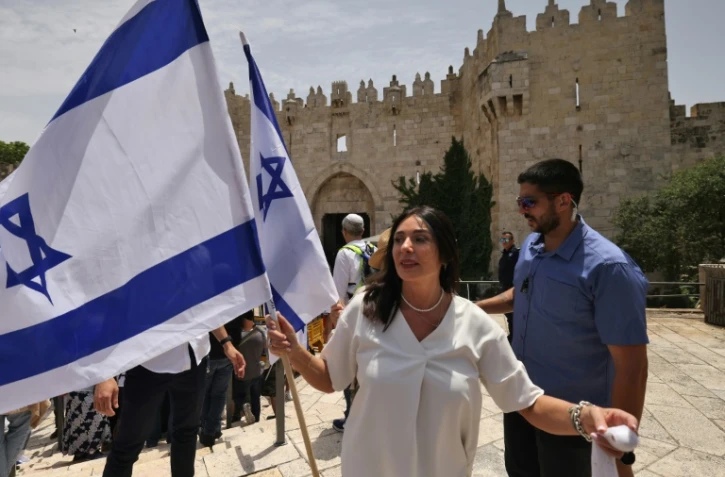 La ministre israélienne des Transports Miri Regev agite le drapeau israélien avant la "marche des drapeaux", devant la Porte de Damas à Jérusalem-Est le 18 mai 2023