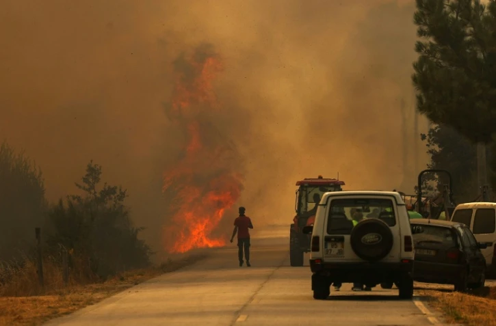 Un homme se dirige vers les flammes sur une route couverte de fumée dans le village d'Antas au Portugal, le 15 août 2025
