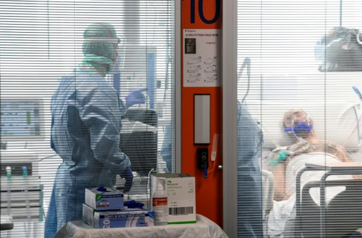 Des membres du personnel médical en combinaison de protection prodiguent des soins à un patient atteint par le nouveau coronavirus dans une unité spéciale de l'hôpital de Brescia, le 17 mars 2020 en Italie
