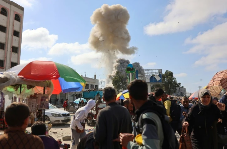 Des Palestiniens regardent la fumée d'un bombardement israélien sur le marché de Firas, à Gaza, le 11 avril 2024