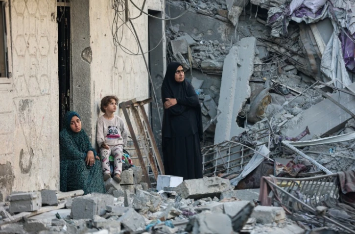 Des femmes et un enfant au milieu des décombres d'une maison détruite lors d'une frappe israélienne nocturne à Gaza, le 29 octobre 2025